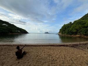 a man sitting on the beach looking at the water at Rasta Rustic Off Grid Cabin in Gros Islet