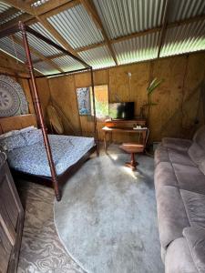 a room with a bed and a couch and a desk at Rasta Rustic Off Grid Cabin in Gros Islet