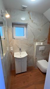 a bathroom with a sink and a toilet and a window at Domki Premium Nad Bałtykiem in Wodnica +3 photos