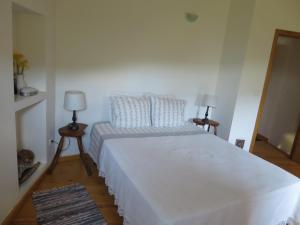 a bedroom with a large white bed and two lamps at Casa das Oliveiras in Colmeal