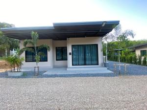 a small house with a gravel driveway in front of it at Cozy Palm Hills in Ban Nong Thale