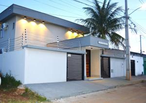 a white house with a palm tree in front of it at Real Grandeza - Studios modernos in Aparecida de Goiânia