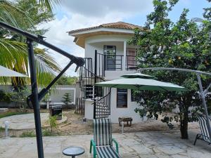 a house with a patio with chairs and an umbrella at Escape Retreats in Diani Beach
