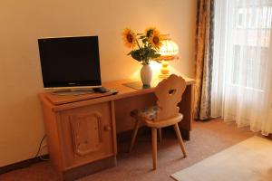 a desk with a computer and a vase of flowers on it at Gemeinschaftshaus im Oberdorf in Lützelflüh +4 photos
