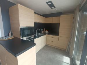 a kitchen with wooden cabinets and a black counter top at Cottage haut de gamme, tout confort in Agde +20 photos