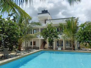 a swimming pool in front of a house with a building at Escape Retreats in Diani Beach