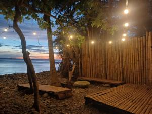 a wooden fence and benches next to the ocean at night at Sunset View Guest House in Camiguin +24 photos