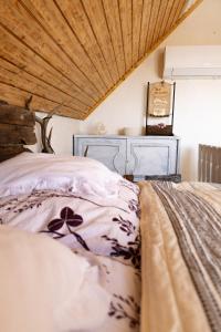a bedroom with a bed and a wooden ceiling at Menyecske Guesthouse in Keszü
