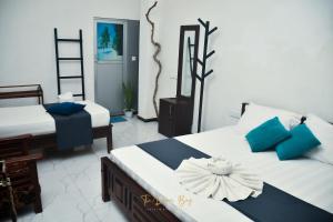 a bedroom with two beds with blue and white pillows at The Dream Bay in Arugam Bay