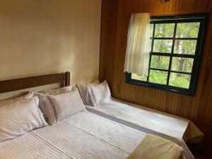 a bedroom with two beds and a window at Campos do Jordão à moda antiga in Campos do Jordão