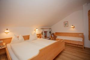 a bedroom with a large white bed and a bench at Ferienwohnungen Wolf in Holzgau