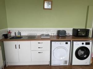 a kitchen with a washing machine and a microwave at Runcorn Jubilee Guest House in Runcorn