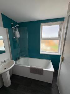 a bathroom with a tub and a sink and a window at Runcorn Jubilee Guest House in Runcorn