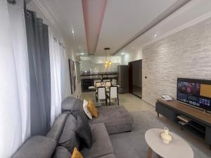 a living room with a gray couch and a tv at House Lima in Lobito