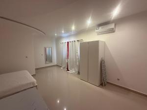 a white room with a bed and a refrigerator at House Lima in Lobito