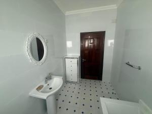 a white bathroom with a sink and a mirror at House Lima in Lobito