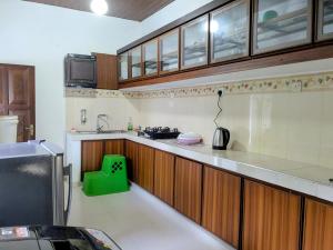 a kitchen with wooden cabinets and a green stool at Prince Cottage - Entire Private Cottage in Kesbewa