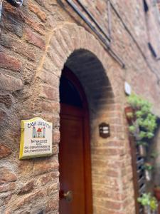 ein Schild an der Seite eines Backsteingebäudes mit einer Tür in der Unterkunft Casa Luisetta in Città della Pieve
