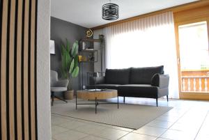a living room with a black couch and a table at Altrove Leukerbad - Modern, Spacious & Central in Leukerbad