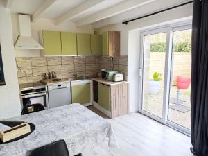 a small kitchen with green cabinets and a table at Gite Les Sables Blancs in Plobannalec-Lesconil