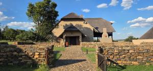 a building with a thatched roof and a stone wall at Vaalkrans Game Lodge in Heilbron
