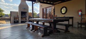 a room with a table and benches and a fireplace at Vaalkrans Game Lodge in Heilbron