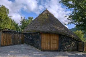 - un petit bâtiment en pierre avec un toit de chaume dans l'établissement Palloza Baltasar, à Castelo