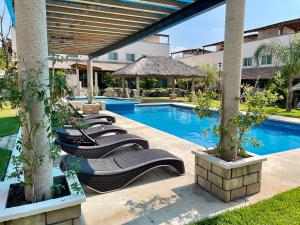 a row of lounge chairs next to a swimming pool at Casa Boho - Heated Pool, Private Grill & Garden - Xochitepec in Tezoyuca