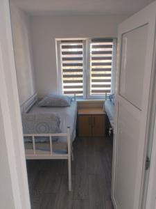 a small bedroom with a bed and two windows at Apartment D&E in Sarajevo
