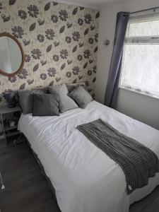 a bed in a bedroom with a mirror and a wall at The Bobbers in Great Yarmouth