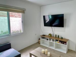 a living room with a flat screen tv on a wall at Casa Boho - Heated Pool, Private Grill & Garden - Xochitepec in Tezoyuca