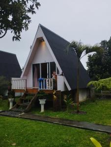a woman standing on the porch of a small house at VILA RINJANI PARADAIS IIn in Sajang