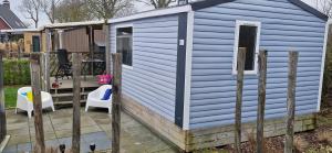 a blue tiny house with two chairs and a table at Chalet B1 900m vom Strand in Koudekerke +8 photos