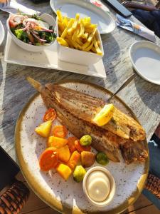 a plate of food with fish and vegetables and french fries at Chalet B1 900m vom Strand in Koudekerke