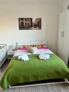 a bedroom with a green bed with towels on it at Il gatto e la volpe 1 in Collodi