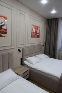 two beds in a room with white walls at Отель Кочевник in Astana