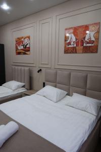 a bedroom with two beds with white sheets at Отель Кочевник in Astana
