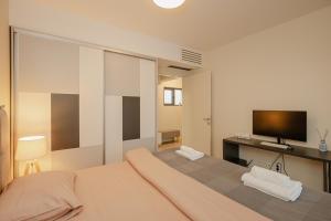 a bedroom with a large bed and a flat screen tv at Ralux apartman Tivat in Tivat