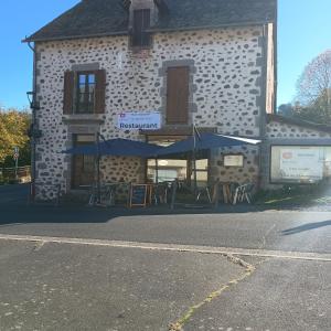 a building with tables and umbrellas in front of it at Rest'ô Bar Les 2 Ponts in Saint-Simon