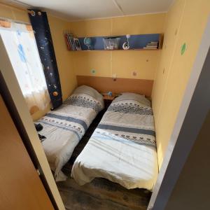 two beds in a small room with a window at Chez Elvis et Agnès, logement climatisé in Saint-Loup +18 photos