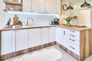 a kitchen with white cabinets and a white rug at Smart apartmány Prešov in Prešov