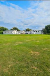 a large grass field with buildings in the background at Westfield 75 in Skipsea