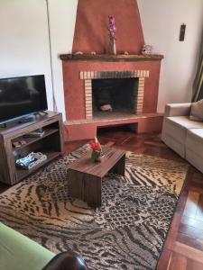 a living room with a fireplace and a tv at Refúgio da Serra - com lareira - 900m do Capivari in Campos do Jordão