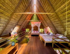 a bedroom in a bamboo roofed room with two beds at Finca Exótica in Carate +33 photos