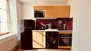 a kitchen with a black refrigerator and a dishwasher at Le Modern Silhouette - Home Homy in Montluçon