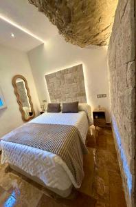 a bedroom with a large bed in a stone wall at Casa Cueva Transmina 10 in Setenil