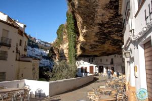 a group of tables and chairs next to a mountain at Casa Cueva Transmina 10 in Setenil