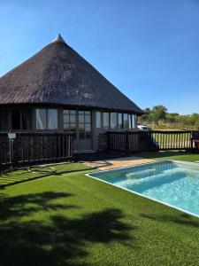 a hut with a swimming pool in front of a yard at Vaalkrans Game Lodge in Heilbron