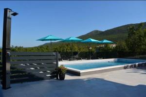 a swimming pool with blue umbrellas at Villa Ika in Gomila +24 photos