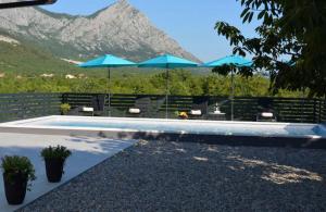 a swimming pool with umbrellas and chairs and a mountain at Villa Ika in Gomila